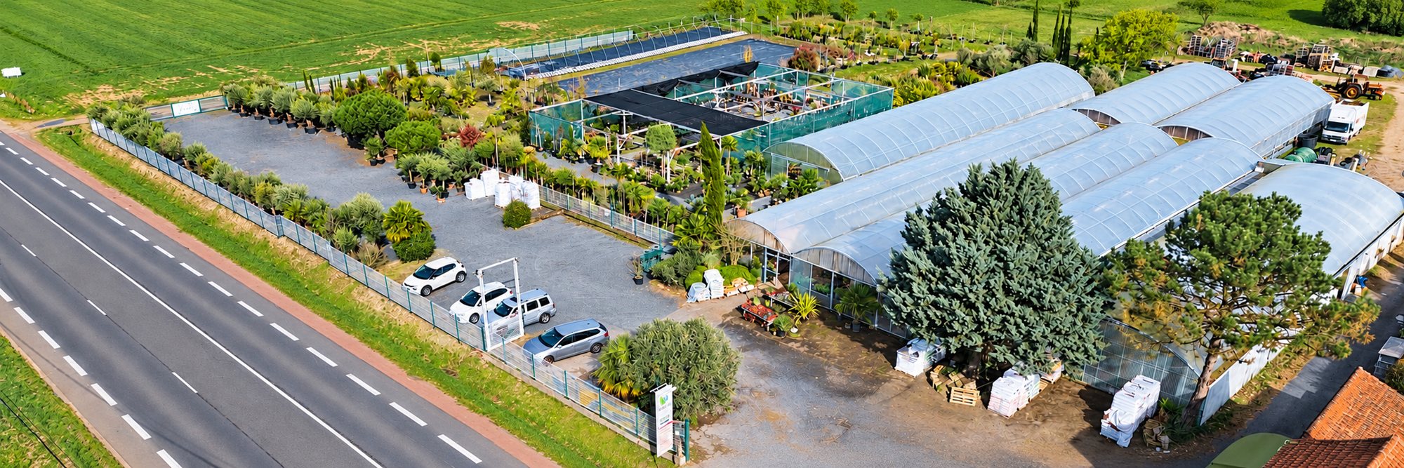 Vue aérienne de la jardinerie, de ses serres et de son parking, depuis la route